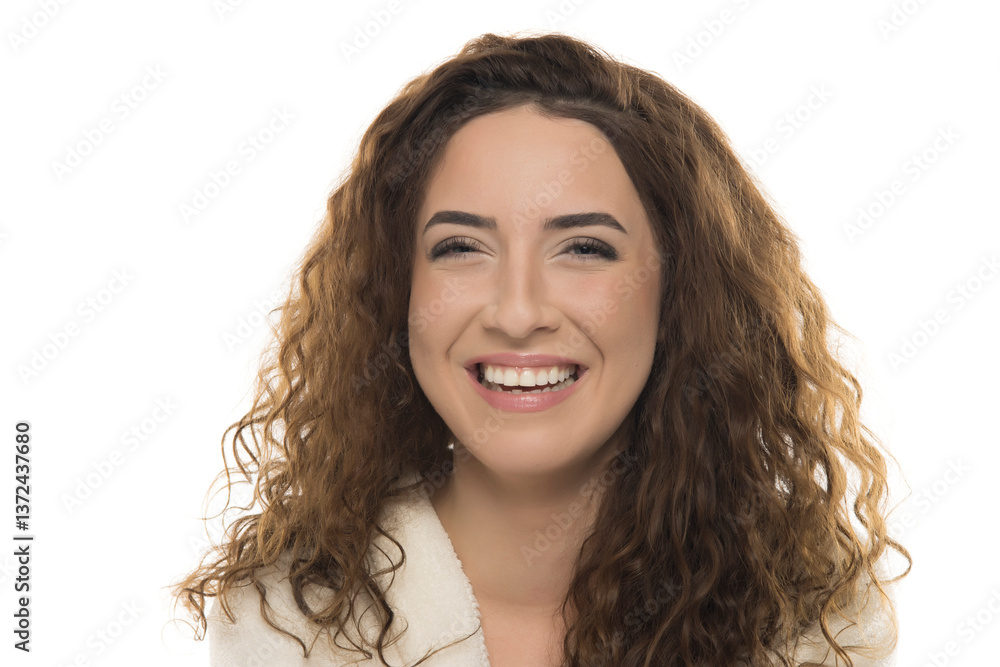 Woman with curly brown hair in white bathrobe smiling warmly against white background, genuine happiness, friendly expression, natural portrait Woman with curly brown hair in white bathrobe smiling warmly against white background, genuine happiness, friendly expression, natural portrait