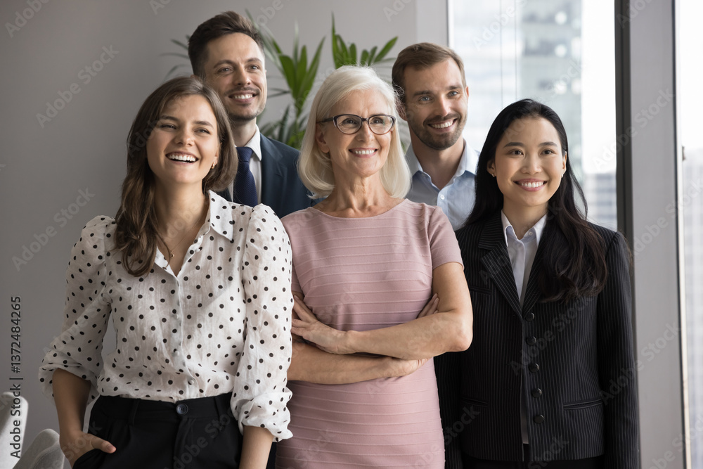 Group of five older and younger satisfied and successful male female colleagues standing together, smiling, looking aside, exude self-assurance and professionalism. Diversity in workplace, teamwork Group of five older and younger satisfied and successful male female colleagues standing together, smiling, looking aside, exude self-assurance and professionalism. Diversity in workplace, teamwork