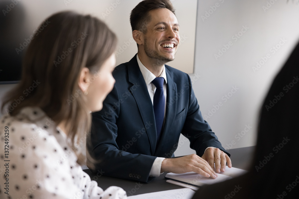 Laughing businessman in suit take part in briefing with teammates sit at conference table, share ideas, listen colleagues thoughts regarding joint project, engaged in productive, successful teamwork Laughing businessman in suit take part in briefing with teammates sit at conference table, share ideas, listen colleagues thoughts regarding joint project, engaged in productive, successful teamwork