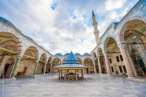 Breathtaking View of the Serene Courtyard and Majestic Minaret of the Fatih Mosque in Istanbul Showcasing Ottoman Architecture with Elegant Arches Domes and a Central Ablution Fountain under a Cloudy