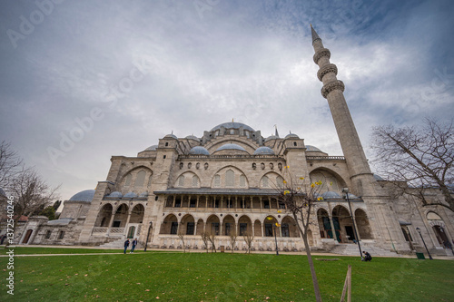 Magnificent exterior view of the historic Süleymaniye Mosque in Istanbul showcasing its grand Ottoman architecture, towering minaret, domes, and serene courtyard under a dramatic cloudy sky