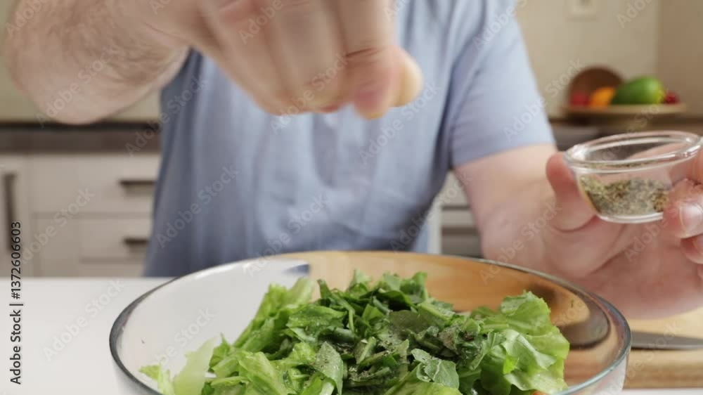 man adding seasoning to vegetable salad,fresh produce, domestic home cooking, indoor table man adding seasoning to vegetable salad,fresh produce, domestic home cooking, indoor table