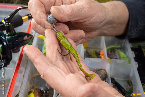 Sport fishing equipment on a table in a studio composition, against a background of a net. A fisherman's hands check the tackle for use.