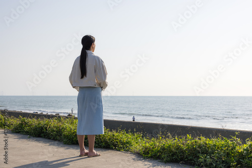 Obraz na płótnie Woman standing alone looking at the ocean w salonie
