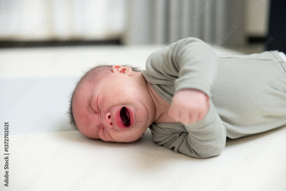 Newborn baby crying loudly on soft carpet