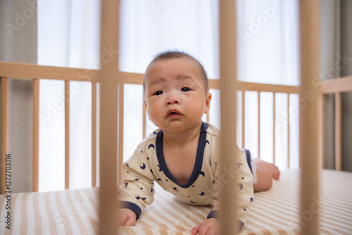 Cute baby crawling inside wooden crib safely