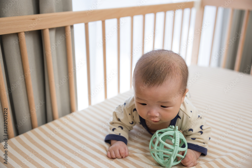 Cute baby playing with toy in crib