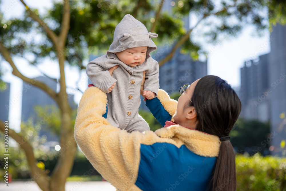 Happy mother holding baby under trees