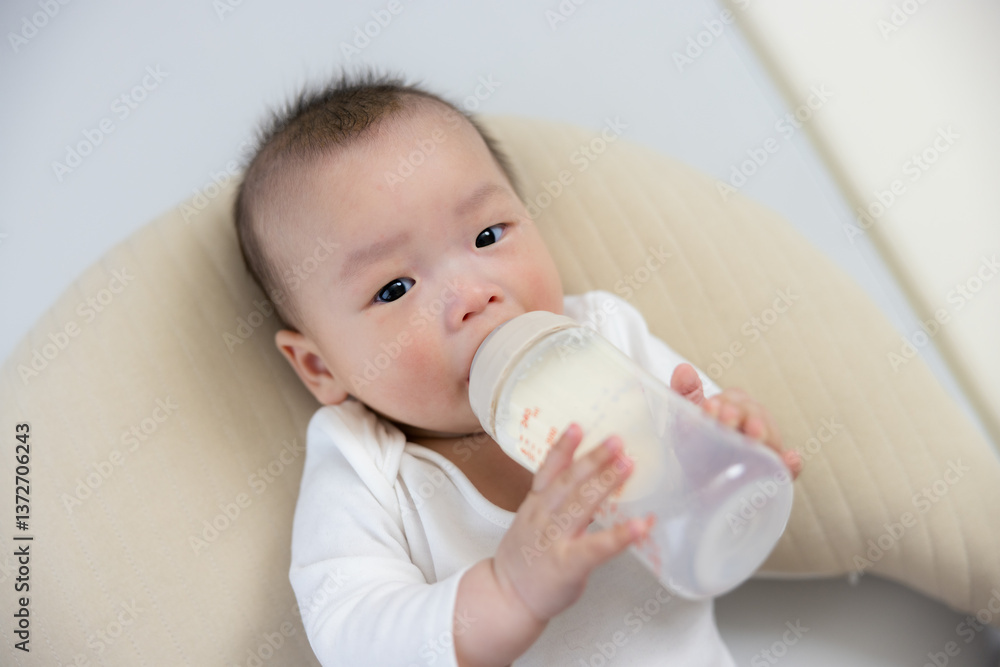Cute baby drinking milk from bottle alone