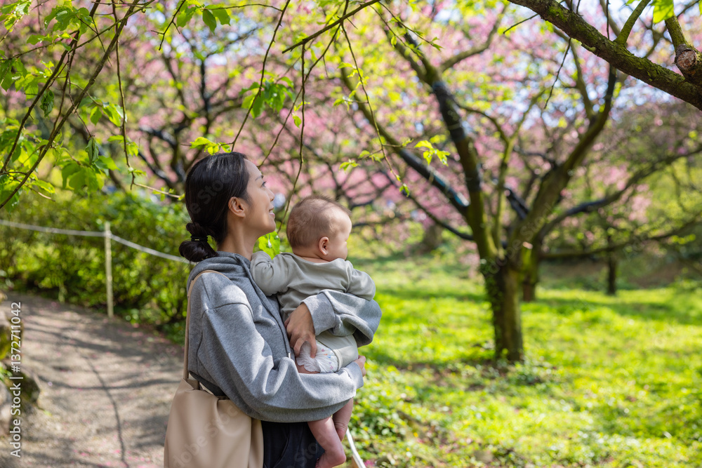 Mother holding baby under cherry blossom trees