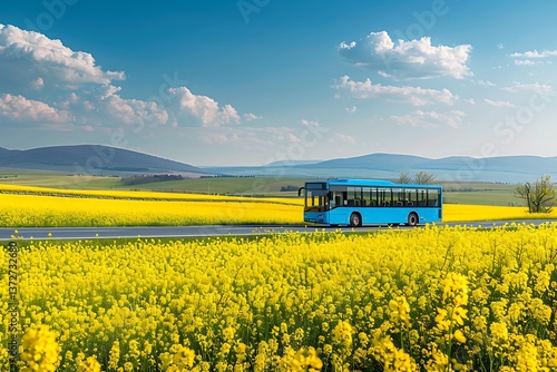 Obraz na płótnie Blue bus traveling on a countryside road surrounded by yellow rapeseed fields w salonie
