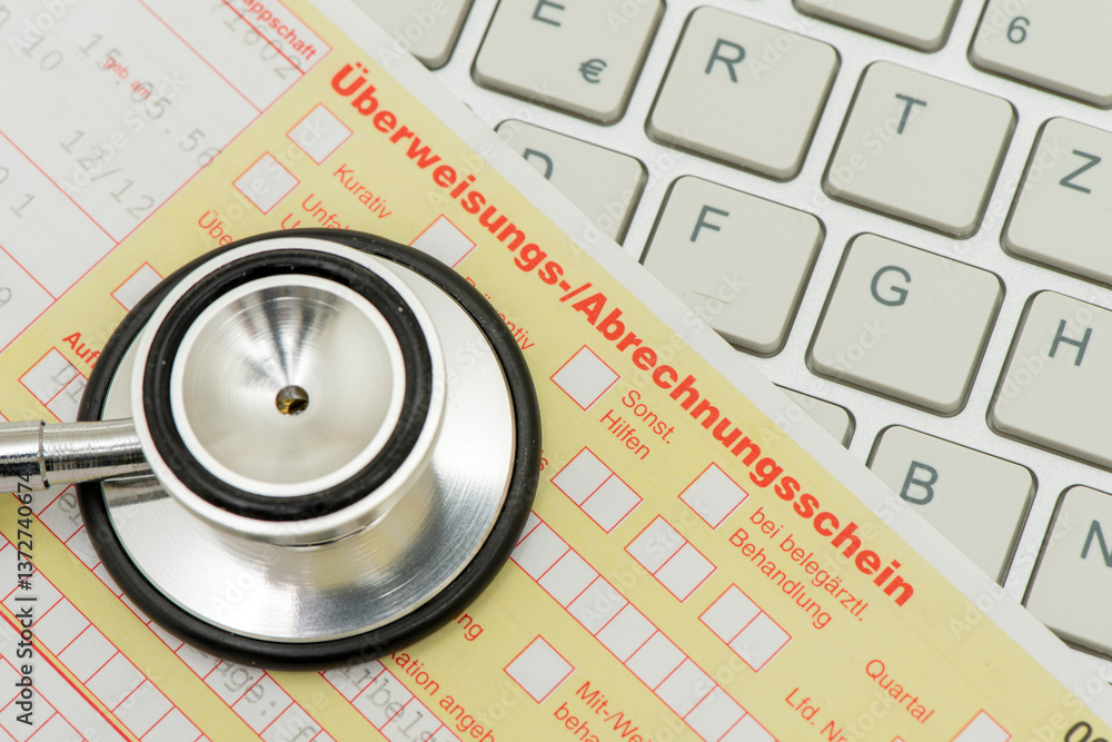 Ein medizinisches Stethoskop und ein Formular für Überweisungs-/Abrechnungsschein liegen auf einer Tastatur als Symbol für Bürokratie im Gesundheitswesen