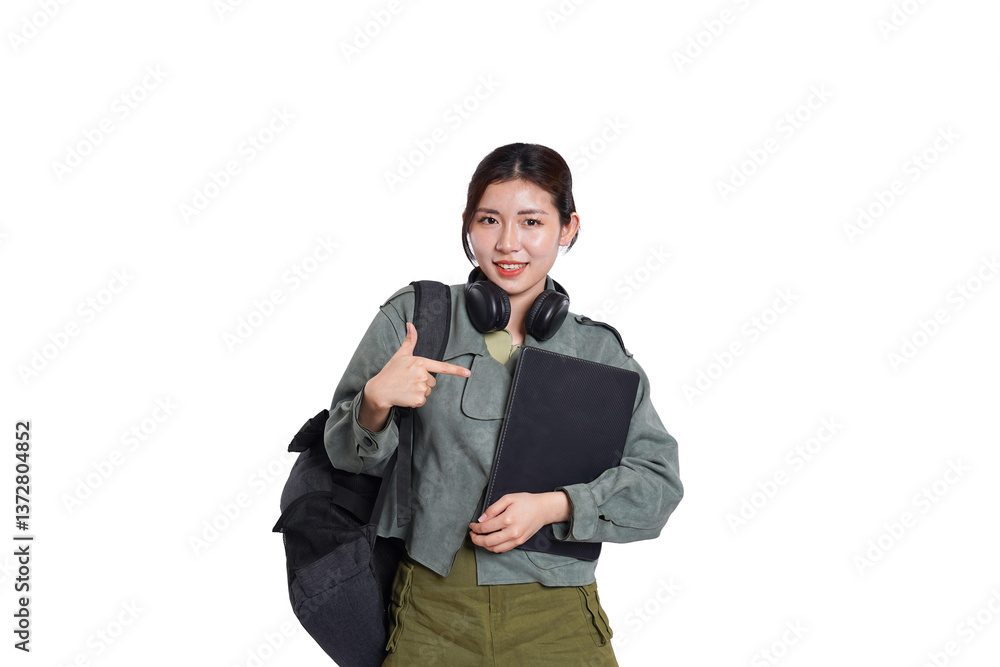 Portrait of Asian female student wearing backpack, headphones, fashionable clothes, holding laptop, posing dynamically on white background Portrait of Asian female student wearing backpack, headphones, fashionable clothes, holding laptop, posing dynamically on white background