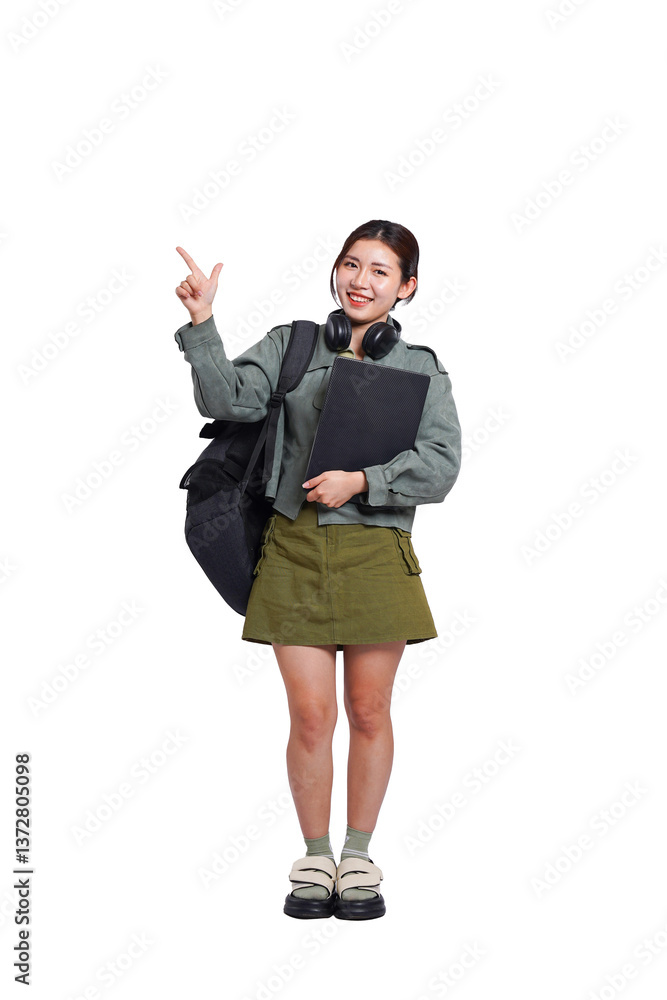 Portrait of Asian female student wearing backpack, headphones, fashionable clothes, holding laptop, posing dynamically on white background Portrait of Asian female student wearing backpack, headphones, fashionable clothes, holding laptop, posing dynamically on white background