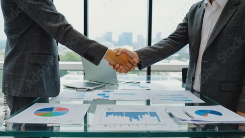 Obraz na płótnie Two businessmen shaking hands over a table with papers discussing a deal or agreement w salonie