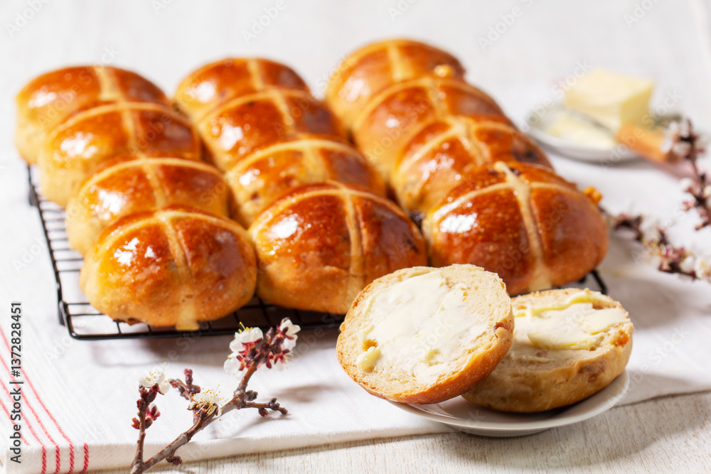 Hot cross buns served with butter and blossoming apricot branches.