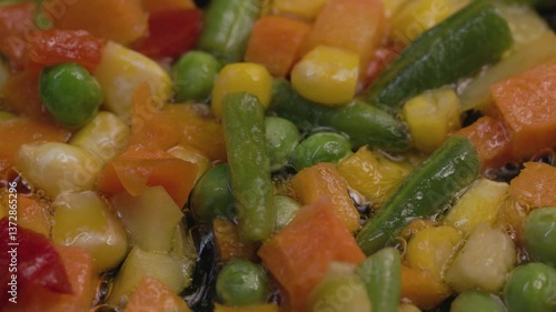 A mixture of frozen vegetables lies in a frying pan, top view.