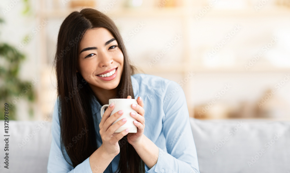 Smiling korean woman drinking coffee while resting on couch at home, looking at camera, enjoying hot drink while relaxing on sofa in living room, spending day-off indoors, closeup portrait, free space Smiling korean woman drinking coffee while resting on couch at home, looking at camera, enjoying hot drink while relaxing on sofa in living room, spending day-off indoors, closeup portrait, free space