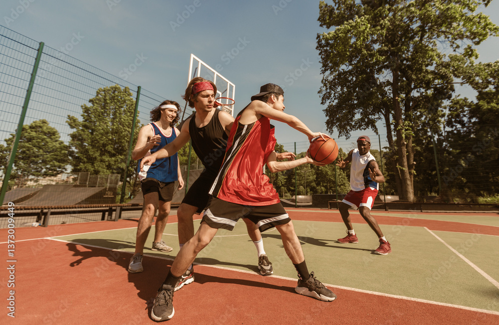 Obraz premium Team of sportsmen playing basketball at outdoor arena