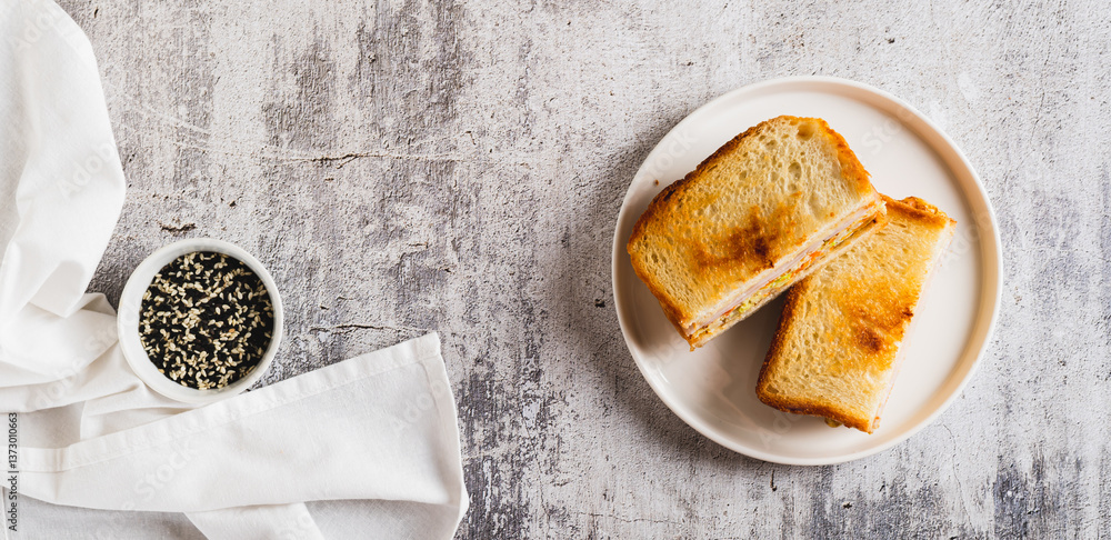 Korean street sandwich with cabbage, ham and cheese on plate on table top view web banner