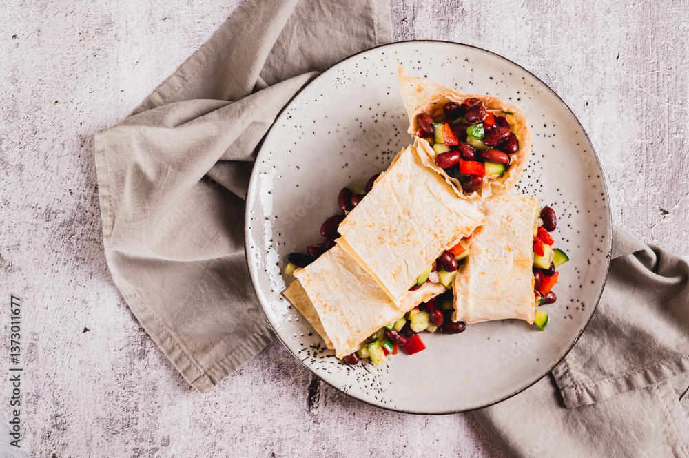 Close up of salad of beans, cucumber and pepper in lavash rolls on a plate on the table top view