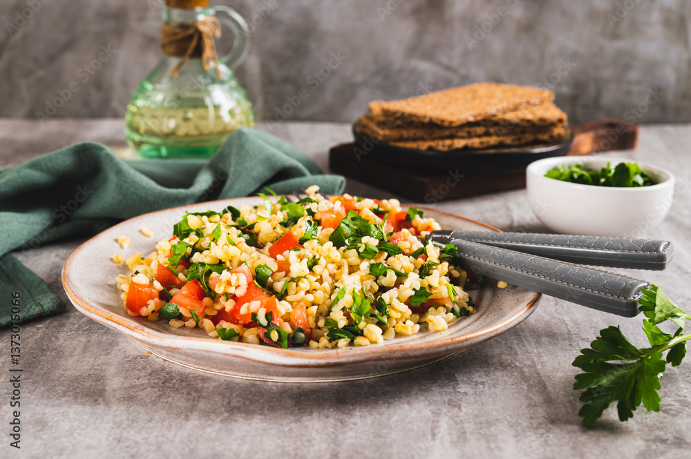 Tabbouleh salad with bulgur, tomato and parsley on a plate on the table