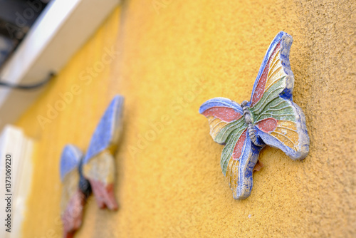Colorful ceramic butterflies on a vibrant yellow wall