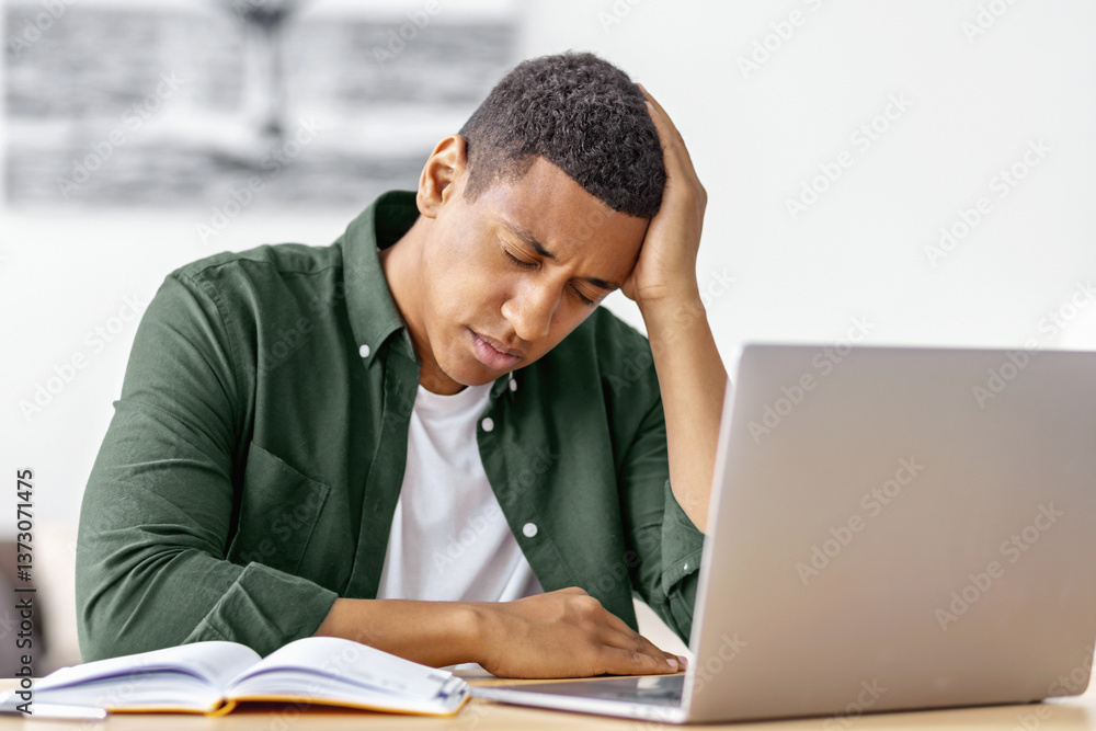 Tired african american man working on laptop