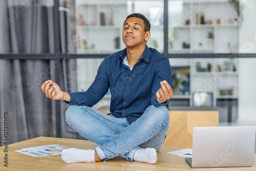 Obraz na płótnie Young man meditating at modern office desk w salonie
