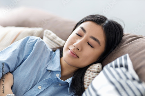 Young asian woman relaxing on cozy couch
