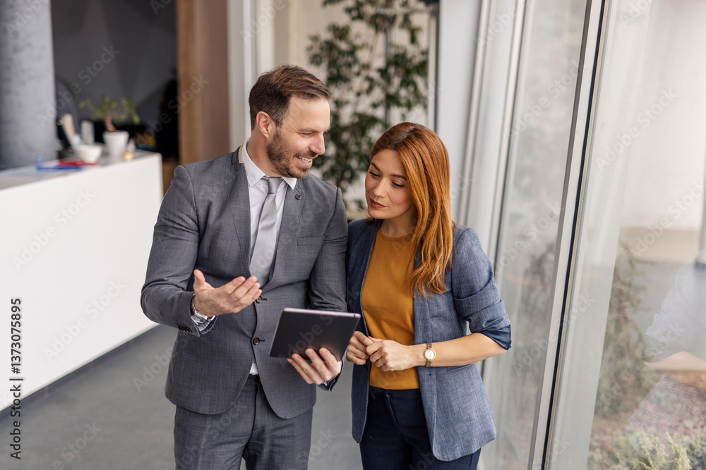 Portrait of businessman with tablet showing businesswoman documentation at corporate firm.
