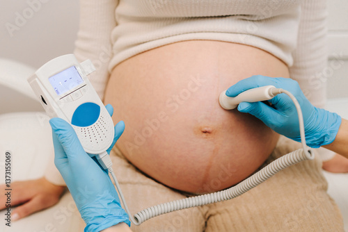 Fotografie Gynecologist listens to fetus heartbeat with fetal doppler in the clinic