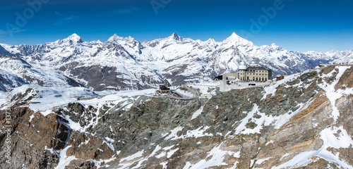 Wallpaper Mural Snow covered Swiss Alps with Matterhorn in the background and Gornergrat Observatory on a rocky ridge under clear blue skies near Zermatt, Switzerland. Torontodigital.ca