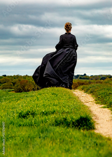 A woman in a black dress is standing on the grass.
