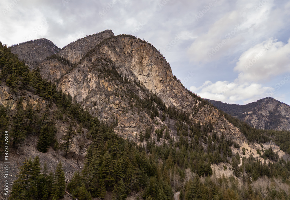 Majestic Mountain Range with Forested Slopes Under a Cloudy Sky Majestic Mountain Range with Forested Slopes Under a Cloudy Sky