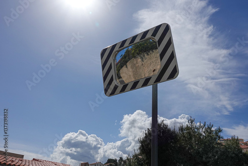 Obraz na płótnie A roadside mirror reflects greenery and a bright blue sky filled with fluffy clouds. w salonie