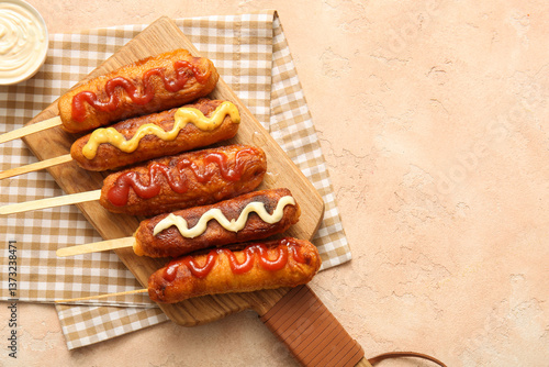 Photography Wooden board of tasty corn dogs with different sauces on beige background