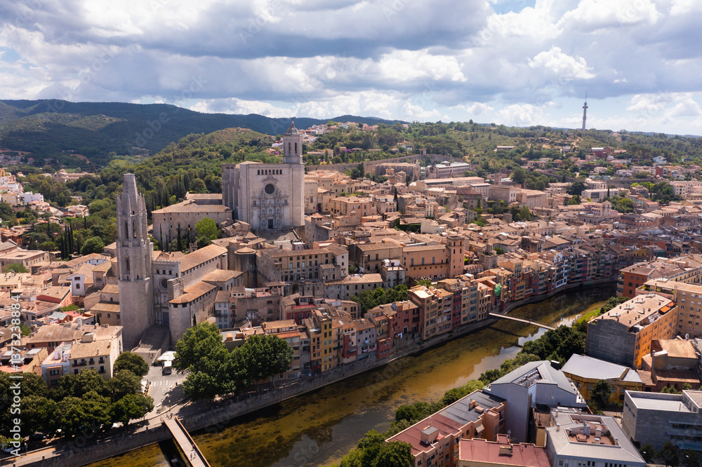 Obraz premium Picturesque view from drone of residential areas of Spanish town of Girona on bank of Onyar river with ancient Gothic Cathedral and Collegiate Church in summer
