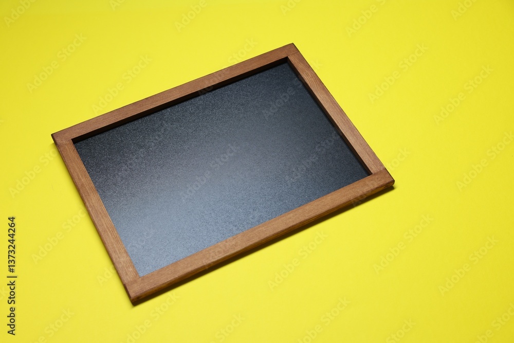 One blank small blackboard on yellow background One blank small blackboard on yellow background