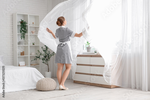 Young chambermaid near wind...