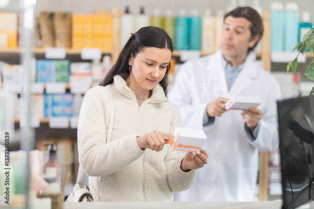Woman chooses pills in modern pharmacy. Male pharmacist helps with choosing a medicine Woman chooses pills in modern pharmacy. Male pharmacist helps with choosing a medicine