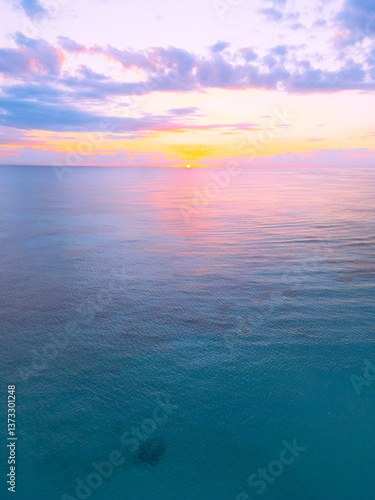 Aerial view of colorful sunrise over ocean in Punta Cana. Breathtaking scenery showcases sky painted with stunning hues, while gentle waves reflect morning light. Perfect postcard capturing tropical