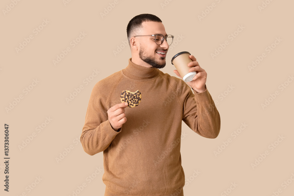 Young man with cookie and cup of coffee on beige background Young man with cookie and cup of coffee on beige background