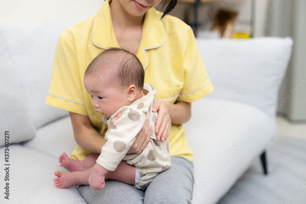 Mother helping newborn baby burp after feeding