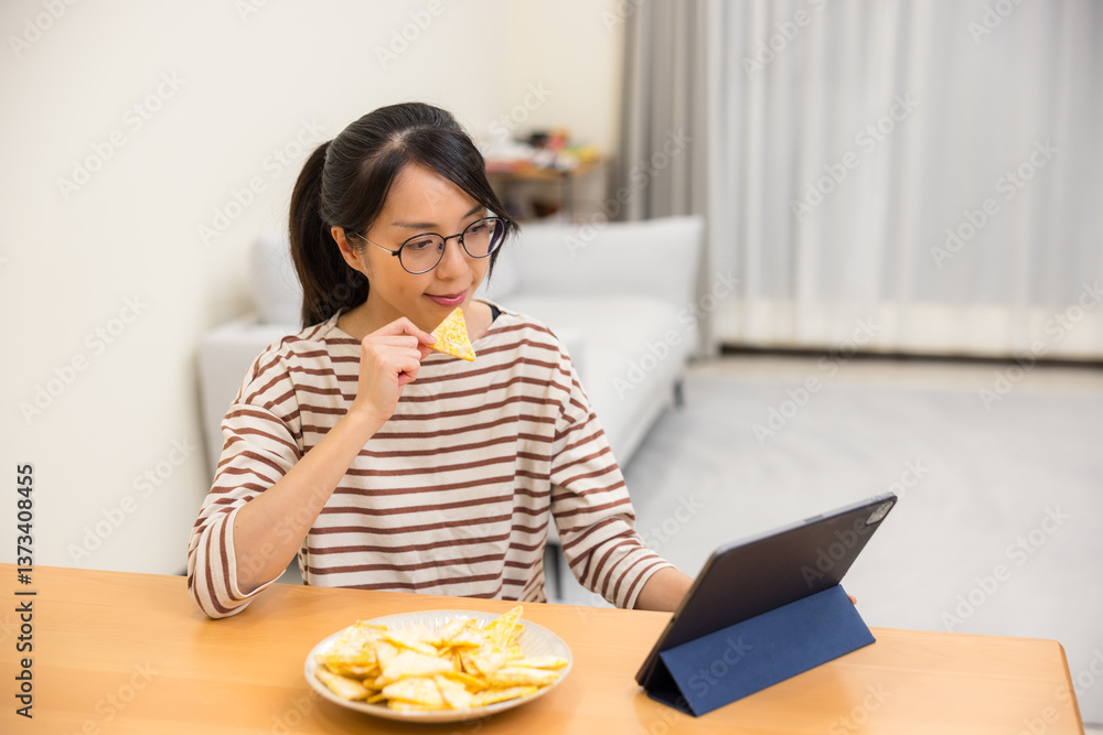 Female enjoying snacks while using tablet at home