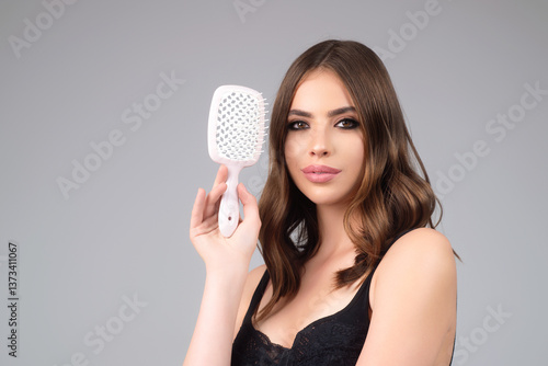 Obraz na płótnie Beautiful woman with brush combing hair. Beauty girl with straight hair isolated on studio background. Woman hold hairbrush near face. Healthy hair. Hairstyle and hair care concept. Shiny hairs. w salonie