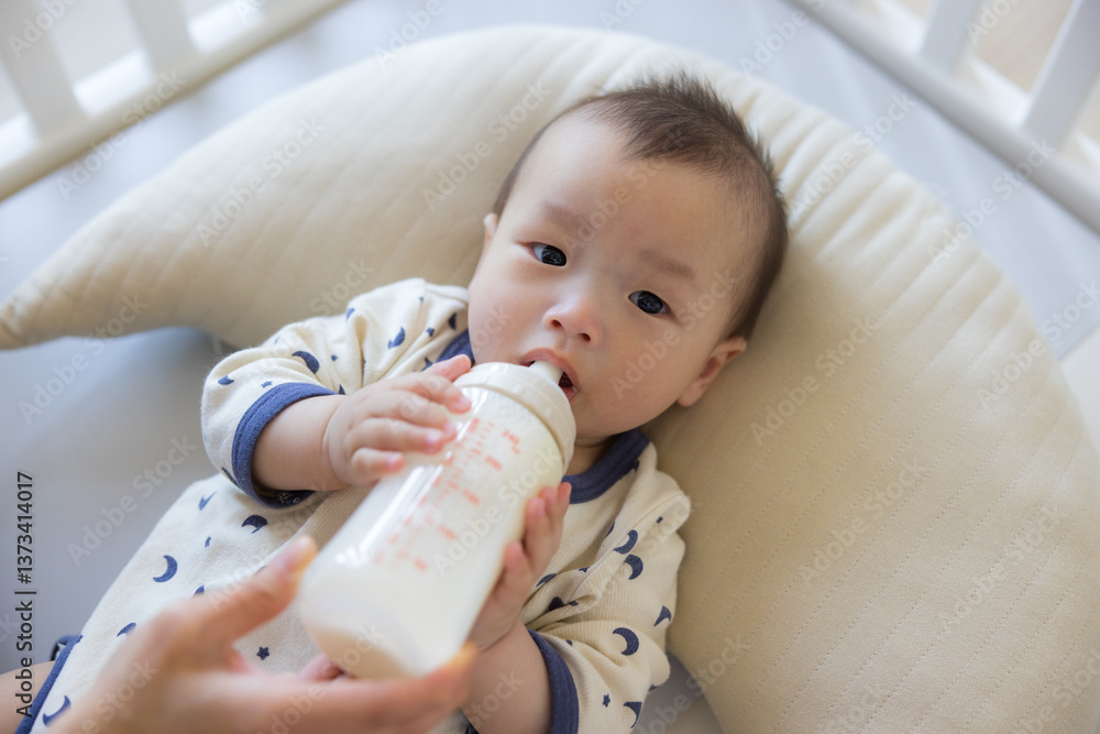 Infant lying on cushion drinking milk