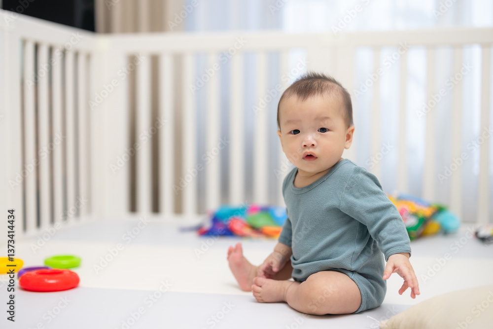 Curious baby sitting in playpen with colorful toys