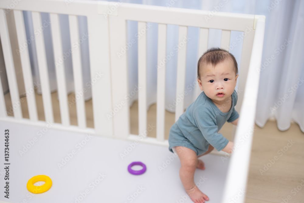 Baby standing inside white crib at home