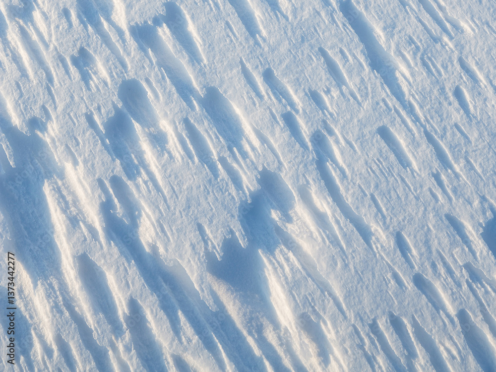 Beautiful winter background with snowy ground. Natural snow texture. Wind sculpted patterns on snow surface.